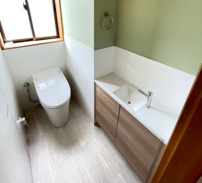 ≪2階トイレ≫<br />
こちらは若夫婦が住まわれると言う事もあり、おしゃれな空間となっております。<br />
天井・壁のクロスは奥様のお好きなグリ－ンで仕上げております。<br />
腰パネルも無地のホワイトサニタリ－パネル張り<br />
床もグレ－を基調としたタイル調のフロアタイル張り<br />
収納付き手洗い器も一体型とし空間に合わせて製作し『ウォルナット色』を選択<br />
トイレはＬＩＸＩＬタンクレス『サティスＳ』を選択<br />
こだわりのオシャレなトイレ空間となっております。